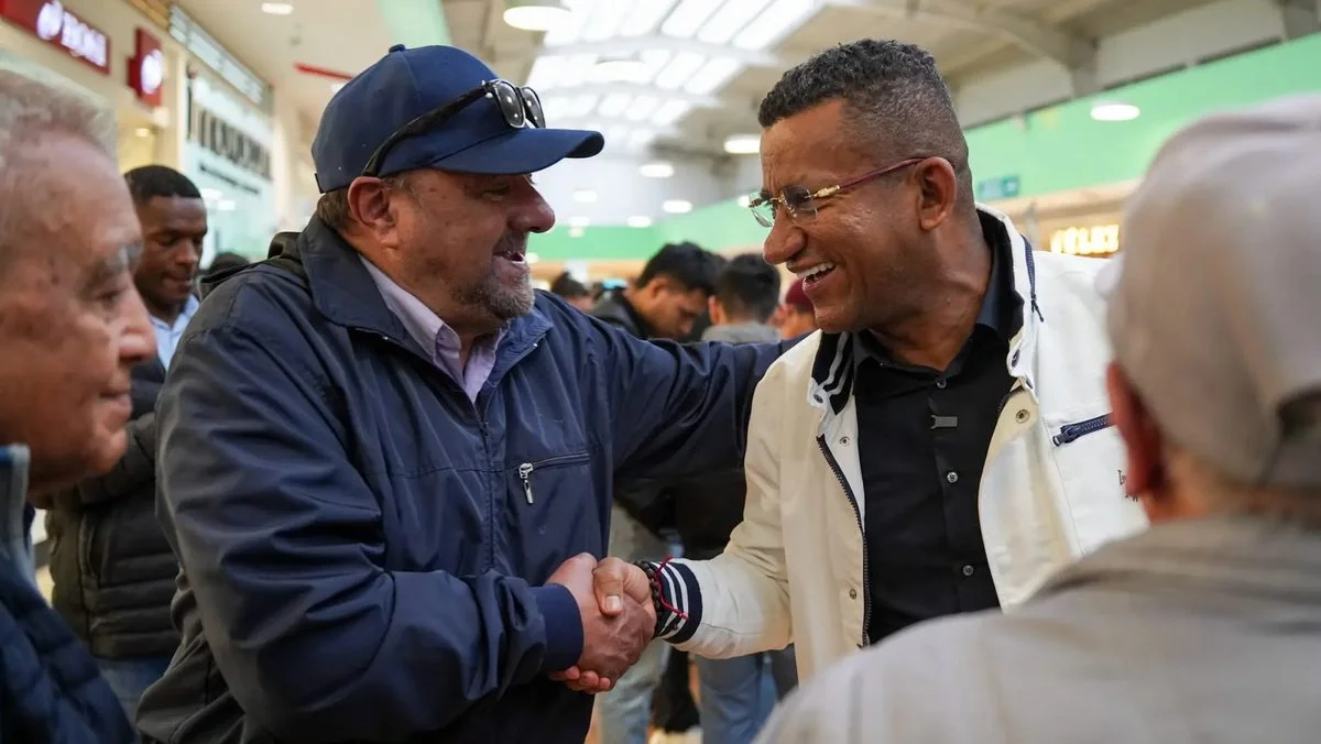 Dos hombres se dan la mano entre asistentes a la feria en el centro comercial de Ipiales