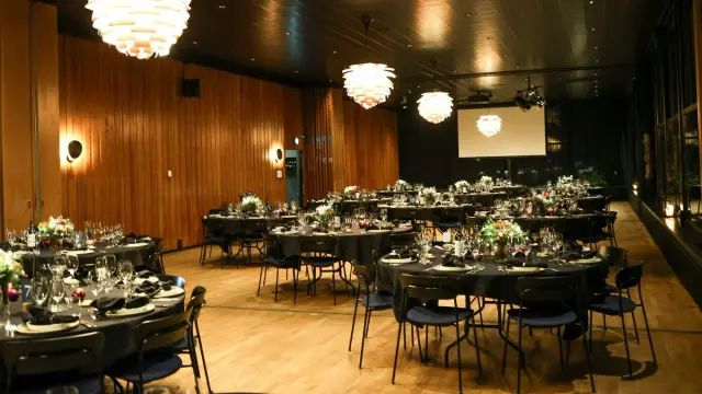 Salón de eventos vacío con mesas redondas servidas para un banquete