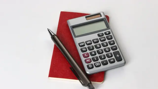 Calculadora y bolígrafo sobre una libreta roja