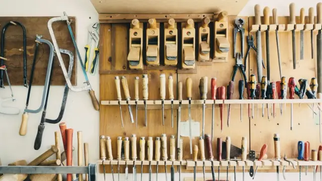 Herramientas de mano ordenadas en un tablero de madera de un taller: sierras, cepillos, formones y destornilladores