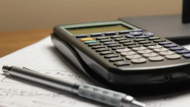 Calculadora y portaminas sobre una hoja con cuentas escritas a mano
