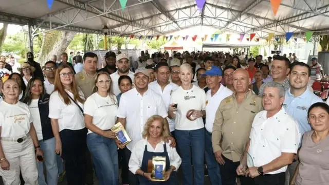 Productores paneleros y funcionarios posan con empaques de panela bajo una carpa durante la entrega en Bugalagrande