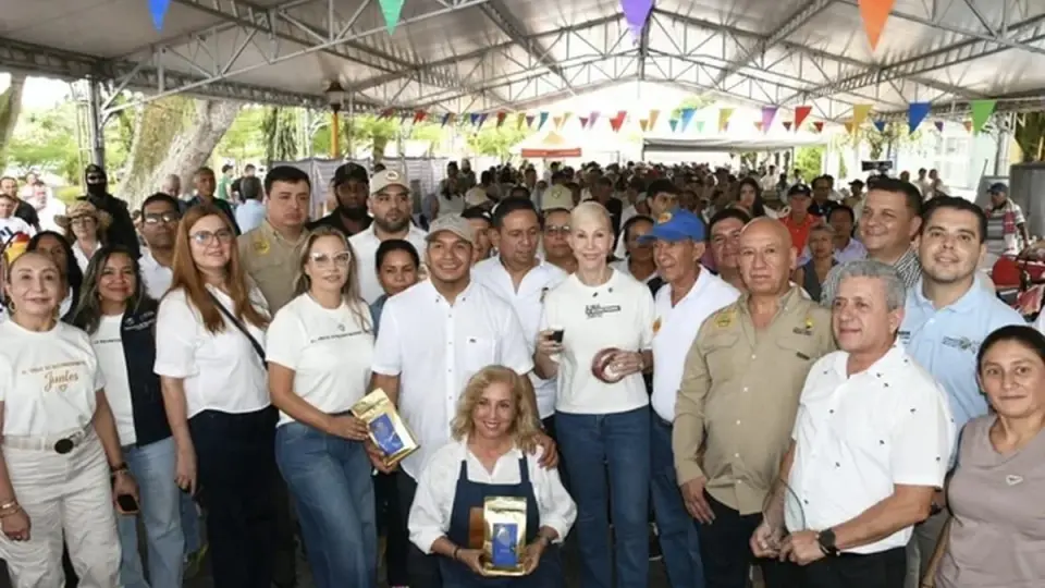 Productores paneleros y funcionarios posan con empaques de panela bajo una carpa durante la entrega en Bugalagrande