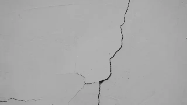 Grieta que atraviesa una pared blanca pañetada