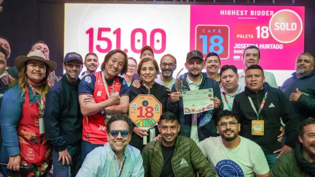 Oscar Navia sostiene el trofeo de primer lugar entre compradores y organizadores, bajo la pantalla de la subasta que marca 151,00 dólares por libra