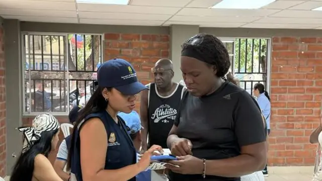 Una funcionaria de la Gobernación con chaleco institucional revisa un documento con una persona afectada durante una jornada de asesoría