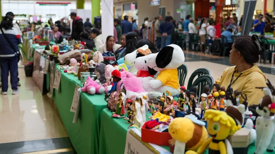 Mesas de emprendimientos con muñecos de peluche y figuras artesanales en el pasillo de un centro comercial de Ipiales, con visitantes al fondo