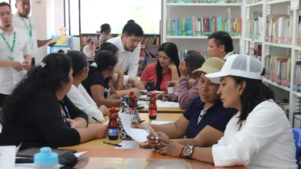 Participantes trabajan con formularios en mesas dentro de una biblioteca de Samaniego durante la jornada de construcción de la política minera