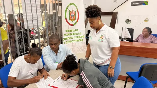 Emprendedores diligencian formularios en una mesa de atención, junto al pendón de la Secretaría de Desarrollo Económico, Turismo y Competitividad de Quibdó