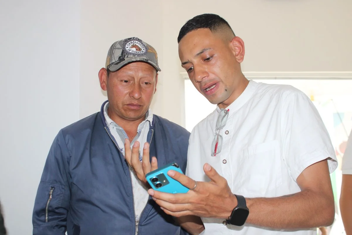 Dos participantes revisan información en un teléfono celular durante la jornada en Samaniego