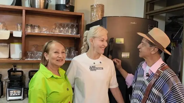 La gobernadora del Valle conversa con una mujer y un hombre de sombrero en la cocina de la cafetería en Sevilla